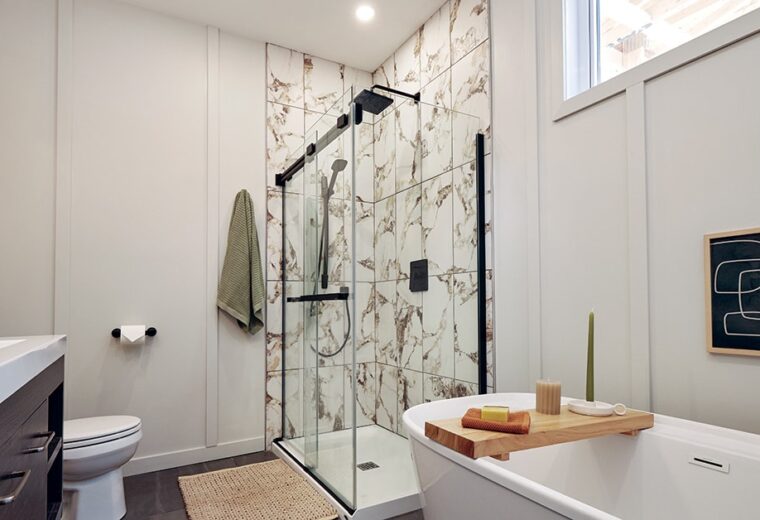 Salle de bain moderne avec baignoire îlot, douche à l'italienne noire et carrelage effet marbre. Ambiance épurée et lumineuse.