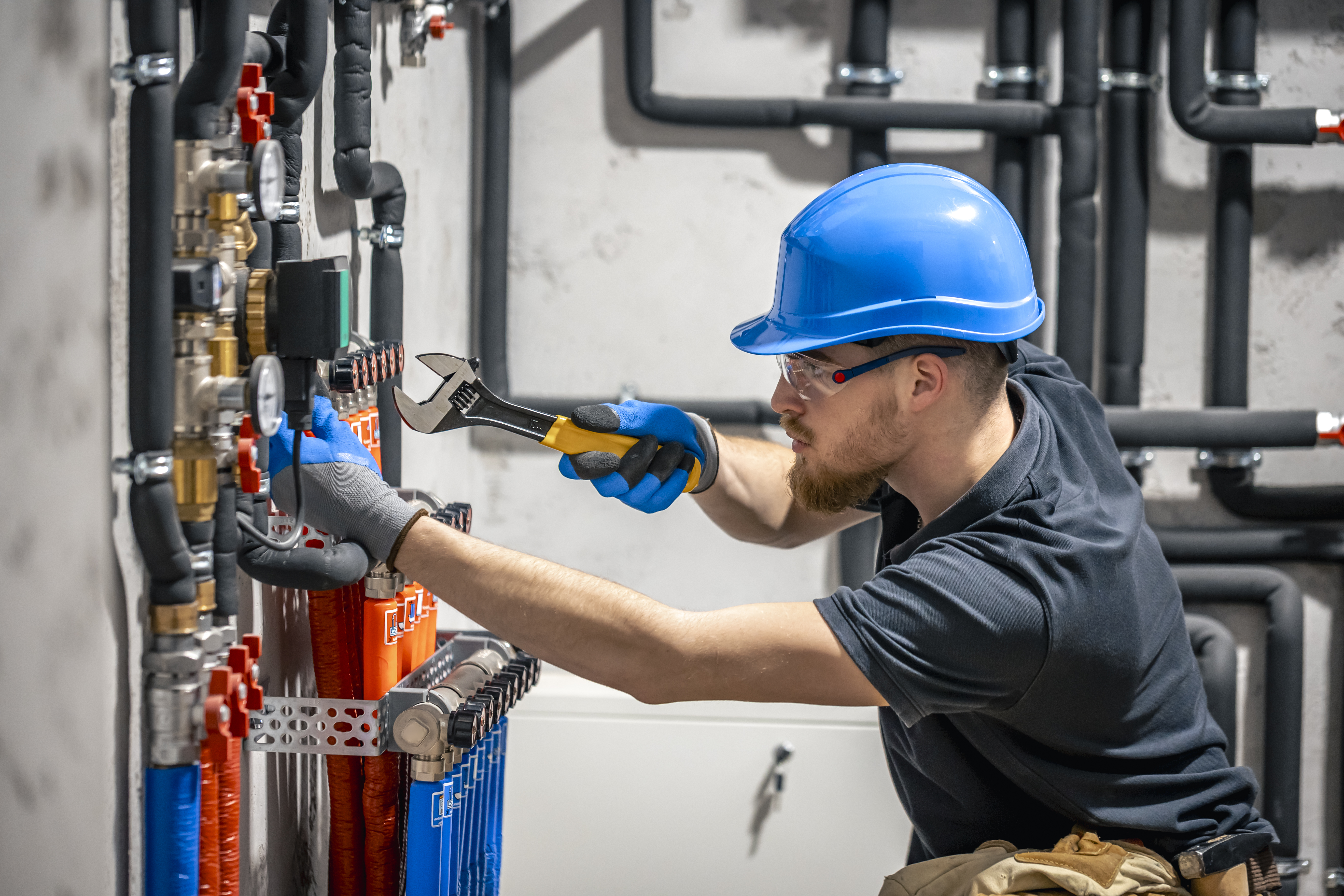 The technician checking the heating system in the boiler room. Adjusting heating valves in a residential building. A plumbing and heating technician works.